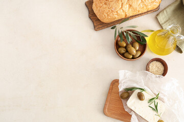 Wooden board with tasty feta cheese, olives, rosemary and bread on white background