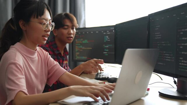 Slow motion back end software developer engineer for computer programming working together on debugging writing computing code, solving complex algorithms display on monitor in office. Burgeoning
