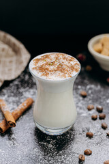 Creamy spiced milk drink in a stylish glass, topped with cinnamon and coconut flakes