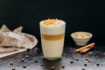 Gourmet layered latte with whipped foam, orange zest, and spices, served on a rustic dark surface