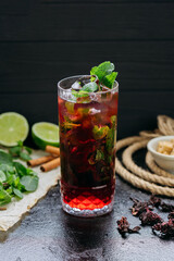 Refreshing hibiscus cocktail with lime, mint, and ice in a tall glass, summer and tropical vibes
