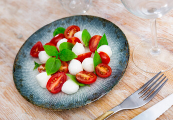 Appetizing caprese salad of fresh vegetables with tomato and mozzarella served on platter
