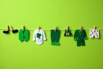 Felt St. Patrick's Day clothes on a clothesline, including a green vest, shamrock shirt, green...