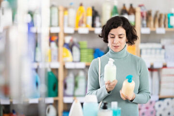 Adult woman buyer chooses liquid hand soap in household chemicals store