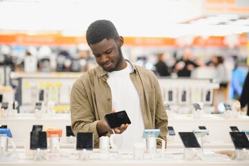 handsome young man buying new mobile in the electronic shop.