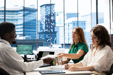 Fototapeta premium Team of HR workers interviewing man to ensuing his qualifications align with company expectations. Coworkers in office meeting selecting applicant based on previous work resume