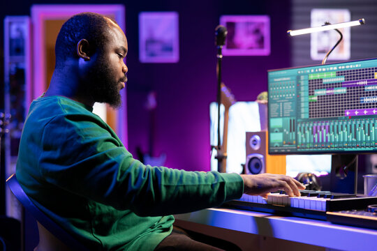 Musician playing piano keyboard and recording tracks for mix and master session, using digital software on pc to create new songs. Sound producer composing music with midi controller tool.