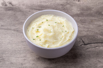 Mashed potatoes in a bowl over wooden table