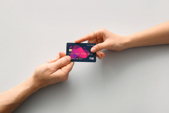Couple holding credit card on light background, top view