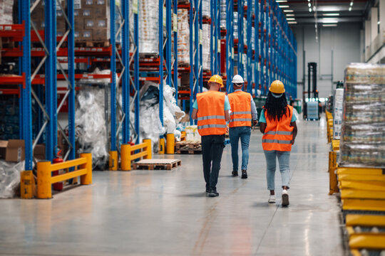 Warehouse workers walking through storage compartment inspecting goods distribution