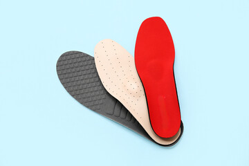 Different orthopedic insoles on light blue background
