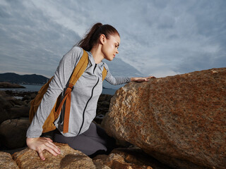 A young woman of mixed heritage exploring rocky shores, dressed in athletic gear, showcasing...