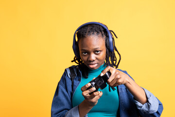 African american gamer holding controller, happily playing videogames, wearing headphones. BIPOC...