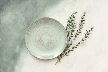 Stylish table setting with plate and plant branches on grunge background