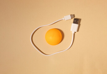 Egg made of ping pong ball and white cable on beige background. Flat lay. Christmas concept.