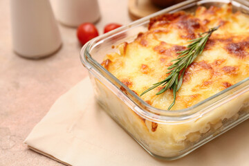 Baking dish with tasty pasta, cheese and rosemary on beige grunge background