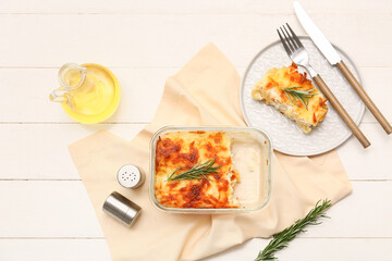 Tasty baked pasta with cheese, rosemary and jug of oil on white wooden background