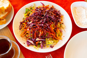 Colorful refreshing crunchy salad from chopped red and white cabbages and grated carrots with olive...