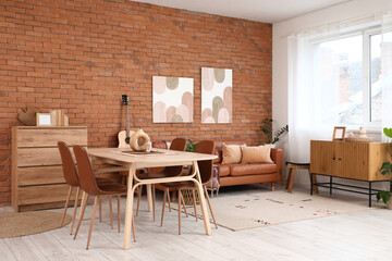 Dining table, chest of drawers and cozy sofa in interior of living room
