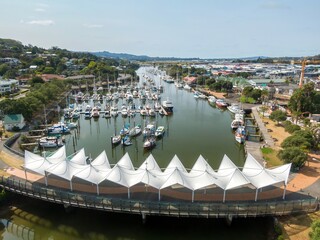 Aerial view of  Whangarei marina with numerous boats, a pedestrian walkway, and modern shelters....