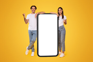 Yes. Excited Couple Leaning On Big Smartphone With Empty White Screen Shaking Clenched Fists,...