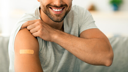 Population inoculation concept. Close up portrait of positive young vaccinated man demonstrating...
