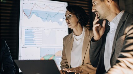 A focused shot showing a team of professionals engaged in discussion with a sleek holographic interface displaying comparative analytics of competitors highlighting key metrics in