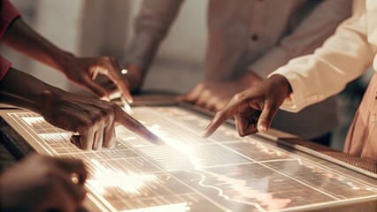 A closeup of a holographic touch interface displaying dynamic charts and statistics. Multiple hands reach out to interact illustrating a collaborative approach to understanding