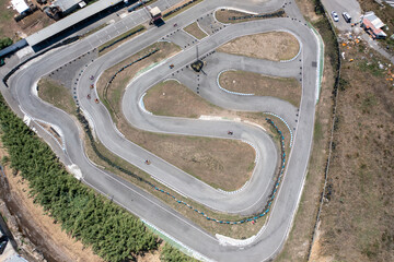 Distant drone capturing go-karts moving on winding racetracks from top aerial perspective. Distant...