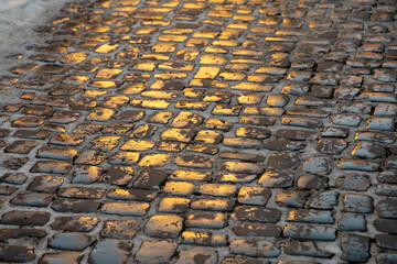 pattern of golden reflection on historic wet cobble stone street in old town in Germany as...