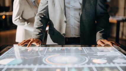 An individual in a sharp suit standing confidently before a holographic dashboard with a 3D pie chart rotating slowly and financial indicators pulsing in vibrant colors.