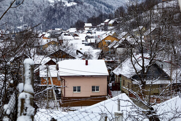 A lot of colorful houses in snowy mountains during winter, surrounded by snow-covered trees. A peaceful countryside scene