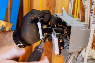 Electrician wearing gloves is connecting electrical switches inside wall box during home improvement
