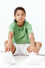 Young boy in green shirt sitting on floor with hands on knees, deep in thought and contemplation