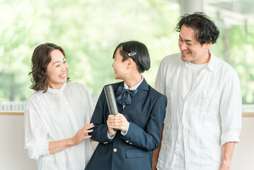 卒業証書を持つ中学生の女の子と両親
