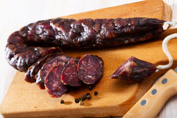 Traditional French dry cured sausage laced with liver on wooden board..