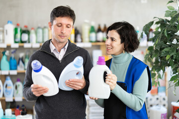 Woman seller gives advice to male buyer, helps to choose laundry fabric softener, and tells...