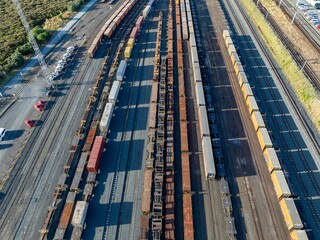 High-angle view of a busy rail yard. Many freight cars and containers are parked on multiple...