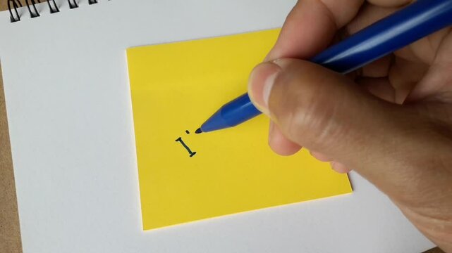 Footage of an illustration of writing the word&nbsp;iam sorry on colored paper. Hand activity holding a pen to write the word iam sorry