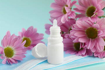 Allergy treatment. Nasal drops, protective masks and flowers on light blue background, closeup