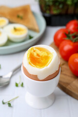 Soft boiled egg on white tiled table, closeup