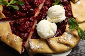 Tasty galette with cherries and ice cream on wooden table, closeup
