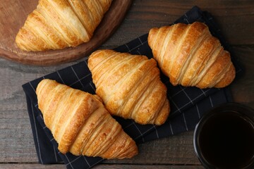 Tasty fresh croissants and drink on wooden table, flat lay