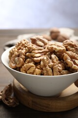 Peeled walnuts in bowl on table against light background, closeup
