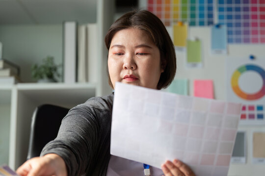 Diverse graphic designer selecting color swatches for a project in a workspace. - Powered by Adobe