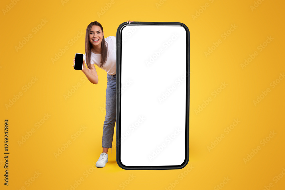 Poster full body length of cheerful woman peeking out standing behind big smartphone with white blank scree