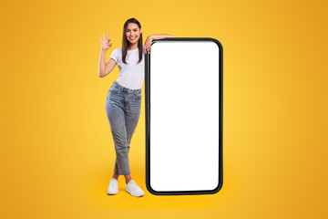 Happy Woman Leaning On Big Smartphone With Blank White Screen And Gesturing Ok Sign, Cheerful Lady...