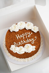 Elegant Birthday Cake with Cream Decorations. Honey cake in a white box for celebration. Top angle view.