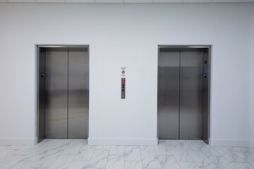 White wall and two elevator stainless steel doors and white marble floor © Francisco