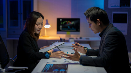 Two people are sitting at a desk, one of them is a woman and the other is a man